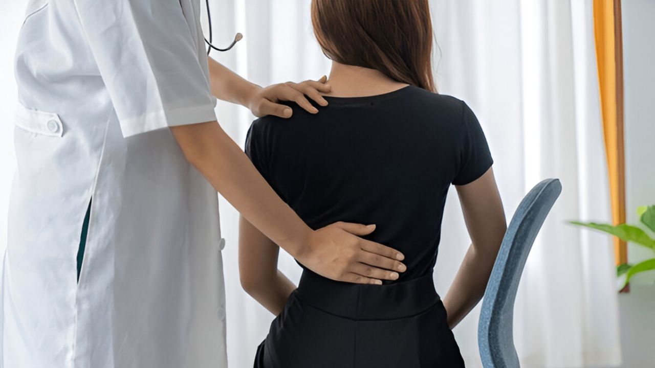 A healthcare provider examining a patient's back, possibly for Sciatica Treatment.