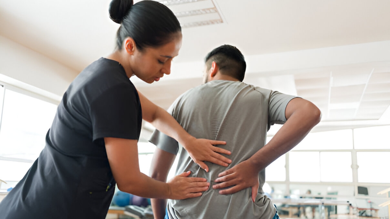 A woman examines a male patient's lower back, indicating back pain relief services at Ridgefield Chiropractic & Wellness Center.