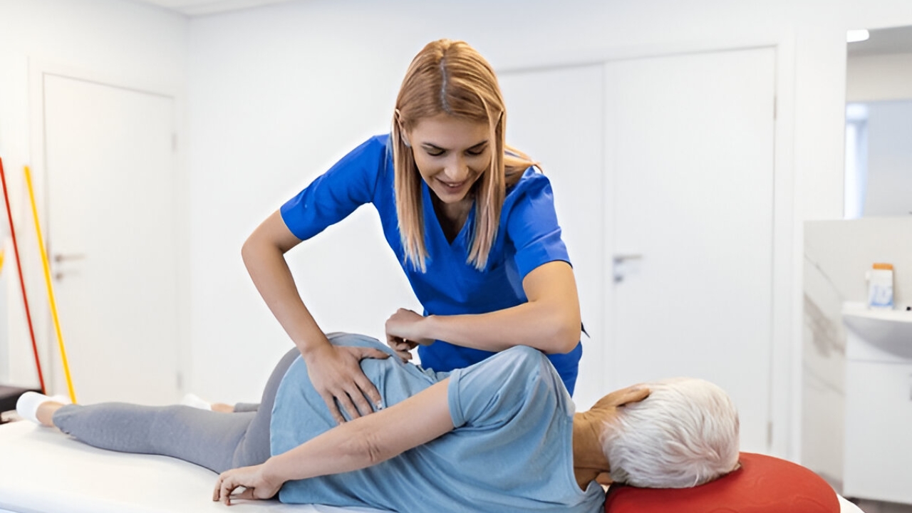 A blonde chiropractor smiles while adjusting an older woman's lower back, a service offered at Chiropractor Ridgefield CT, Ridgefield Chiropractic & Wellness Center.